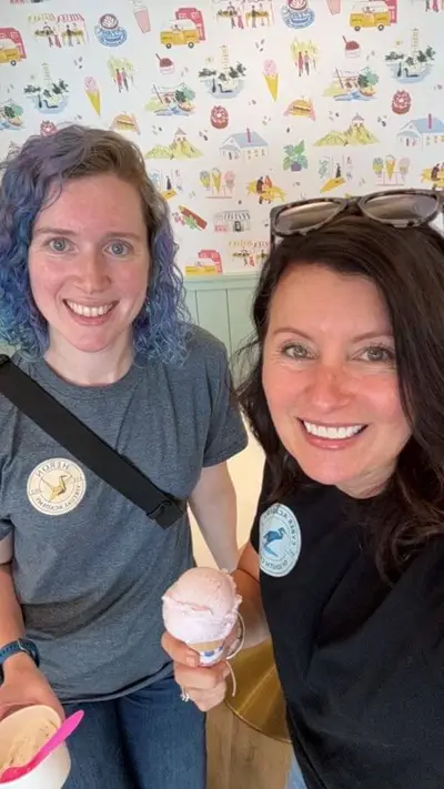 Dos mujeres sonriendo y sosteniendo cucuruchos de helado.