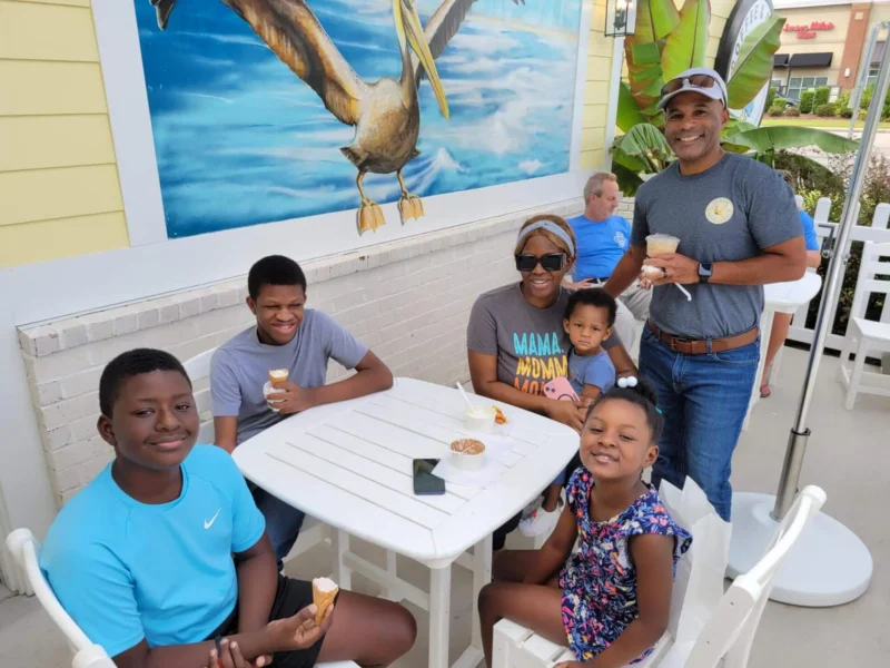 Cuatro niños y dos adultos comiendo helado
